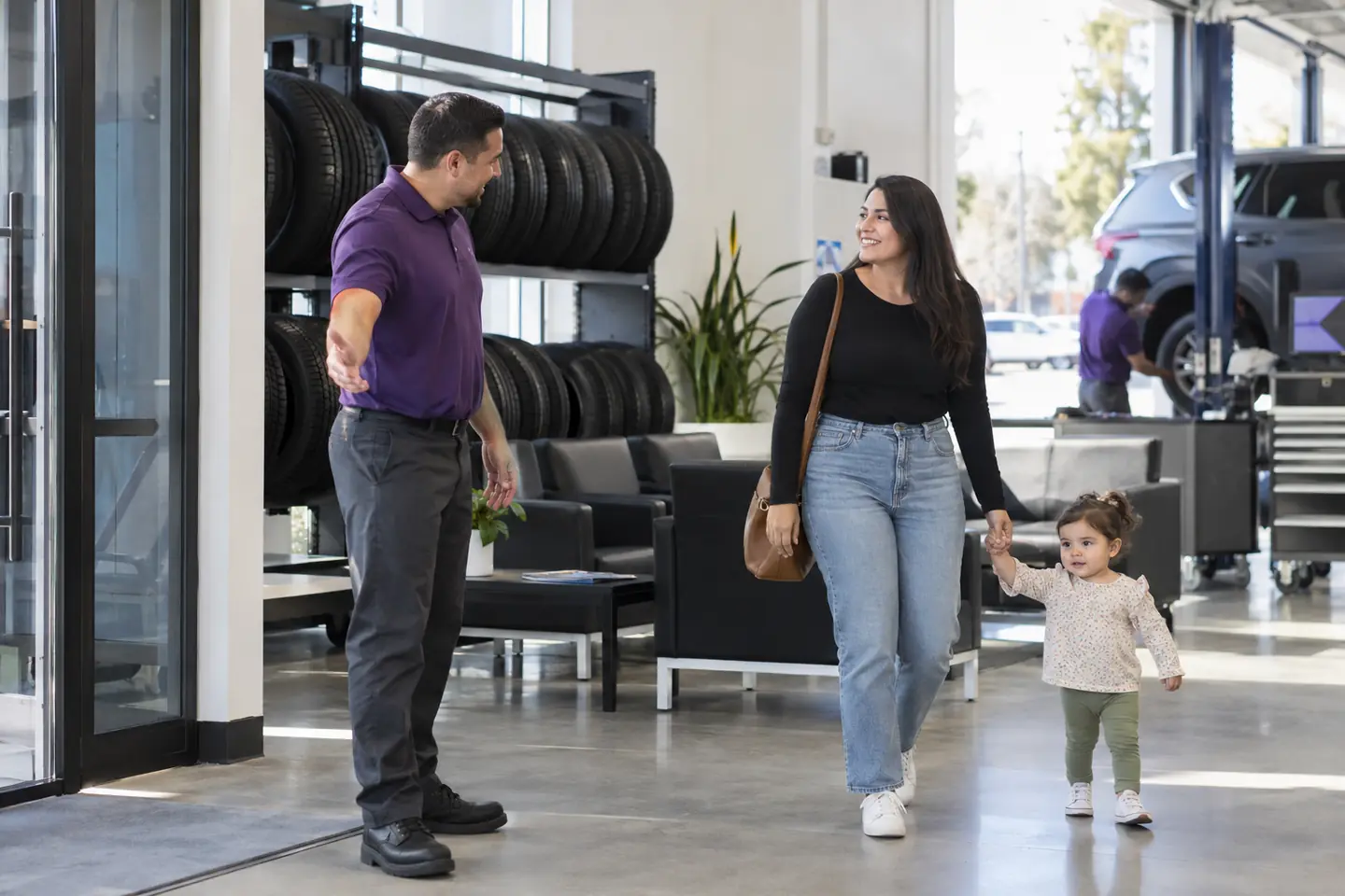A store associate welcomes a mother and her toddler into a bright showroom