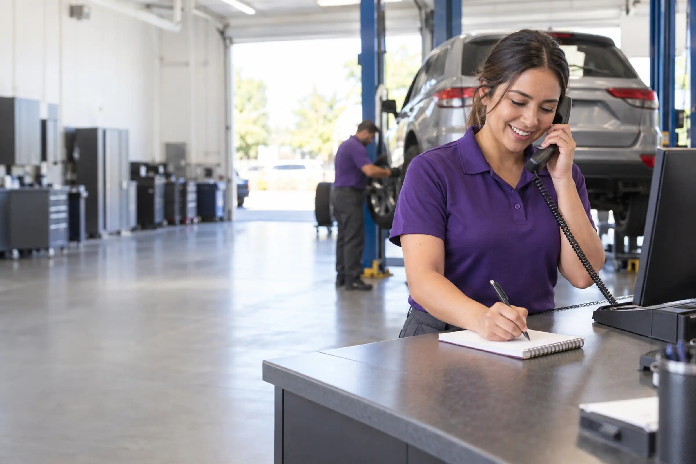 A smiling store associate takes notes on the phone at the service counter