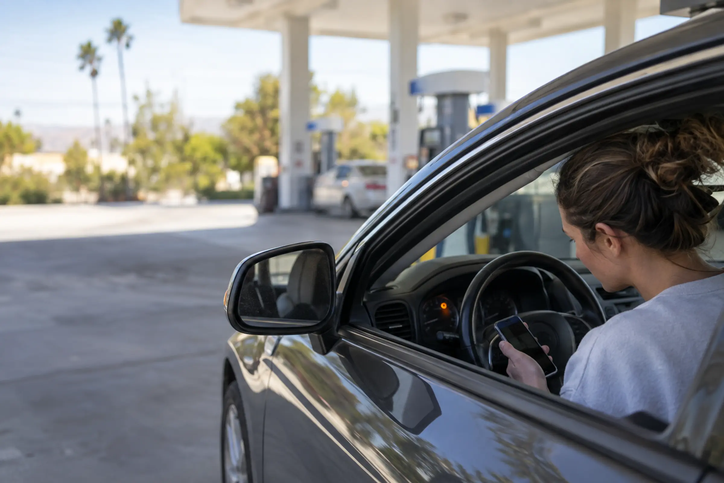 A driver parked at a gas station checks her car before driving on