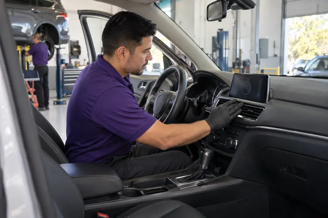 A technician feeling the airflow at a dashboard vent