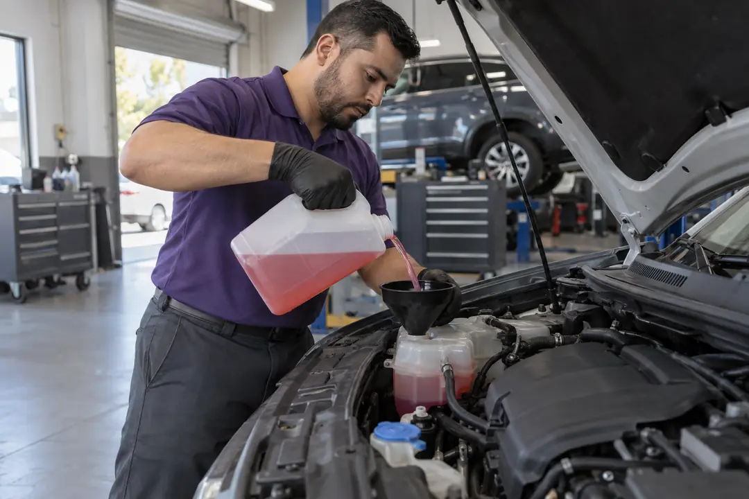 A technician filling a coolant tank through a funnel
